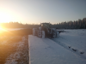 Traktori aurastyössä auringonlaskun aikaan