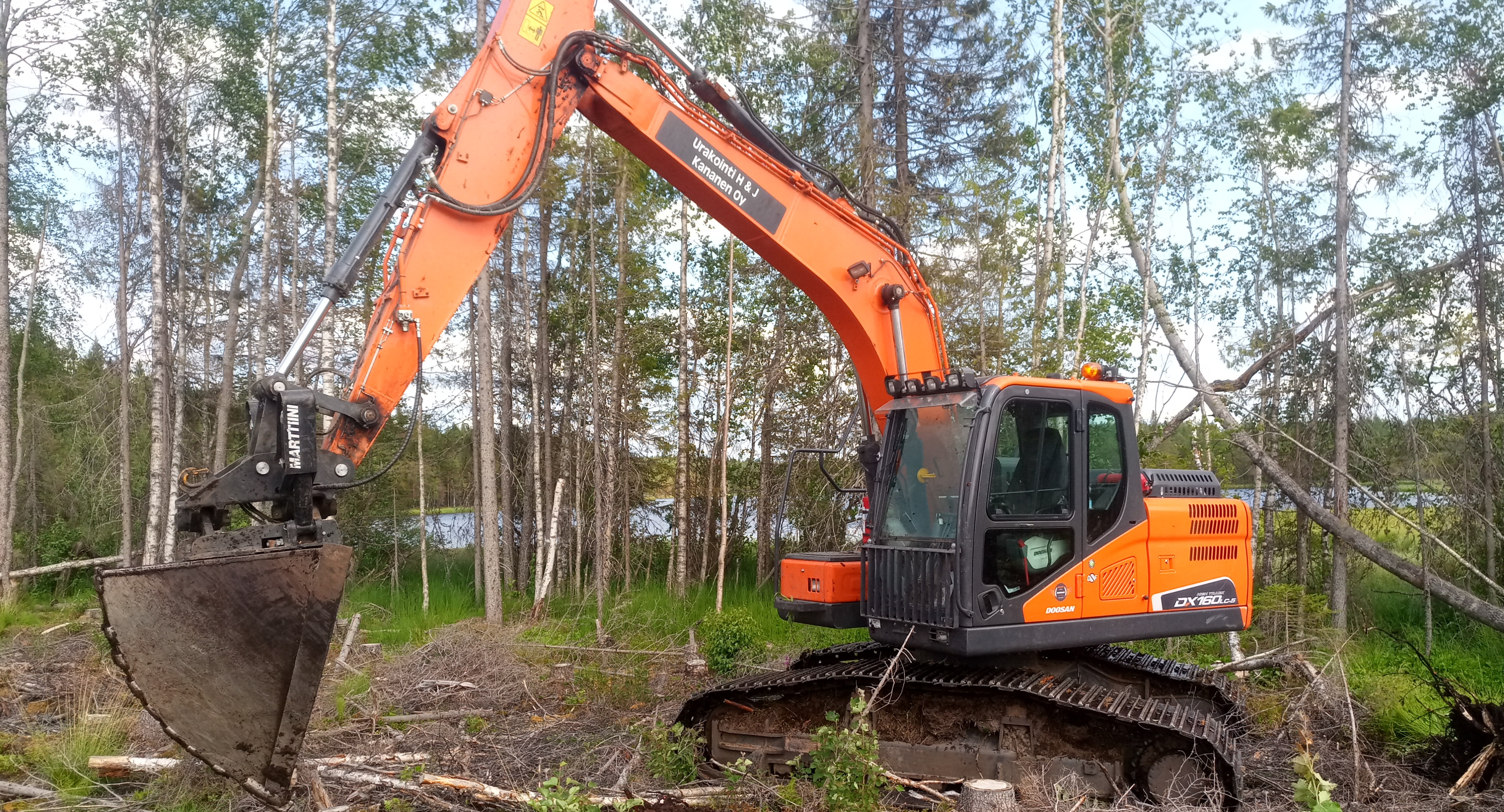 Urakointi H & J Kananen Oy:n kaivinkone metsätyömaalla järven rannalla